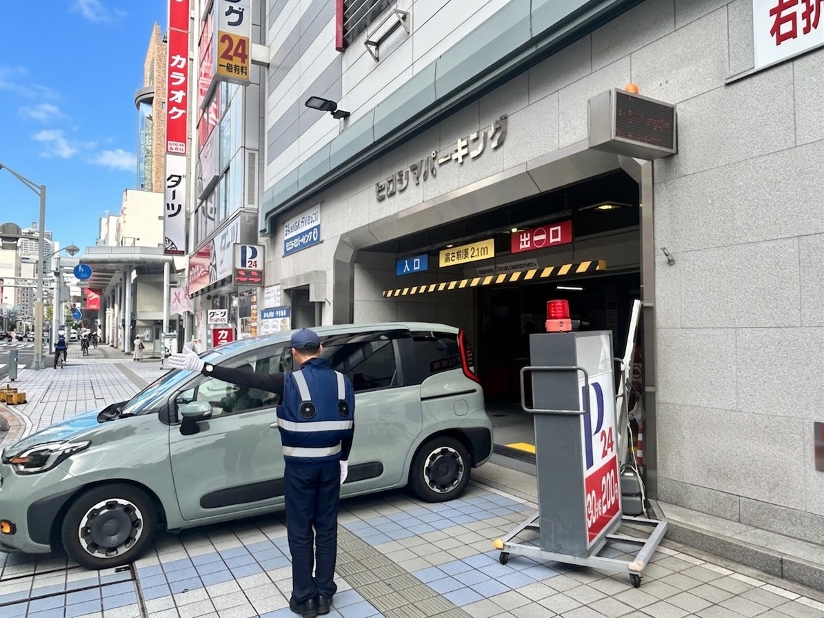 駐車場入口で車両を誘導するスタッフ